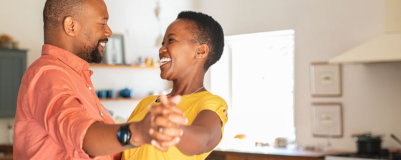 A black man and woman dancing in their kitchen.