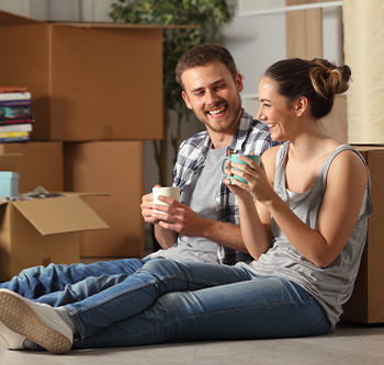 Couple leaning against boxes holding coffee mugs