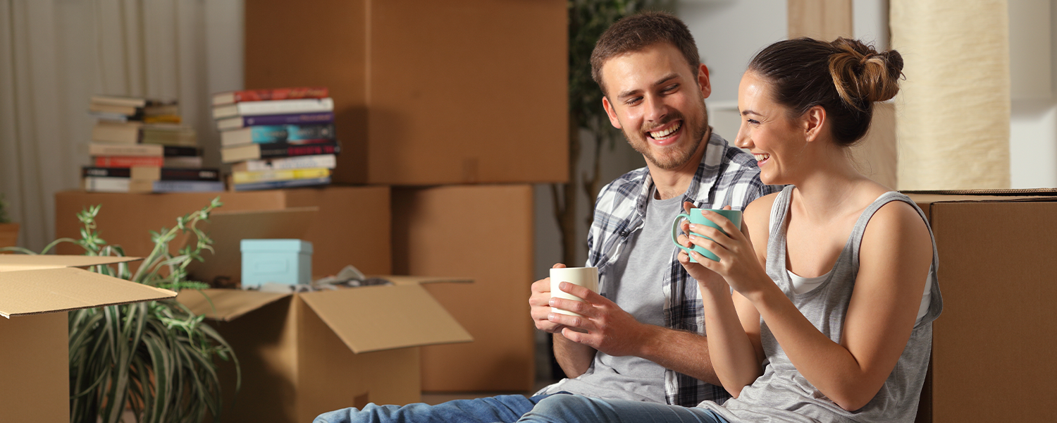 Couple leaning against boxes holding coffee mugs