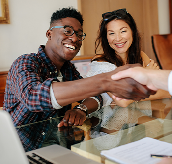 Woman sitting with man shaking hands with agent