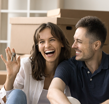 Man sitting with woman holding up keys