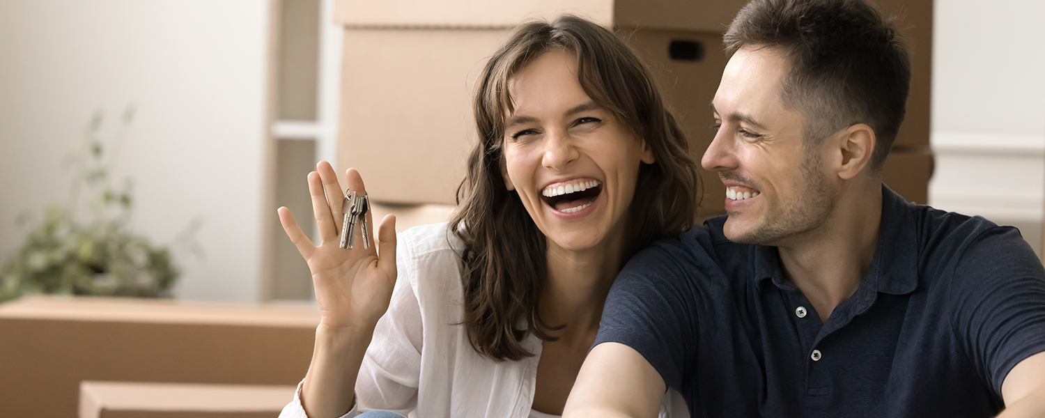 Man sitting with woman holding up keys