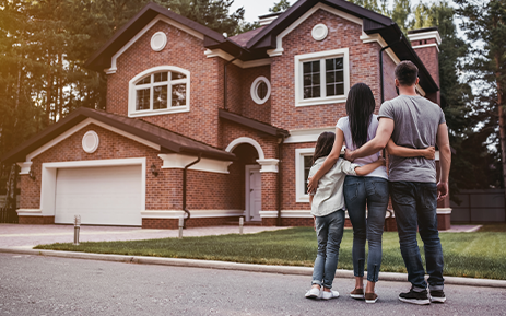 Family standing together looking at house