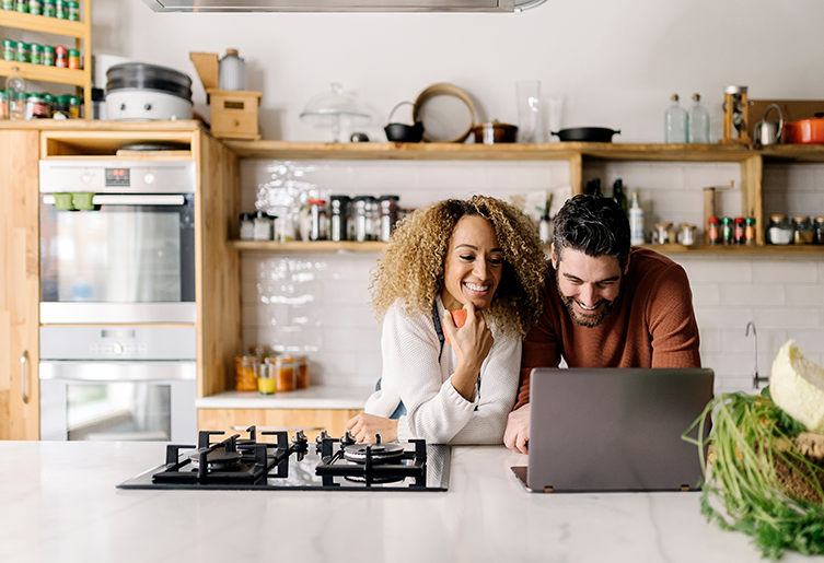 Couple using laptop in kitchen