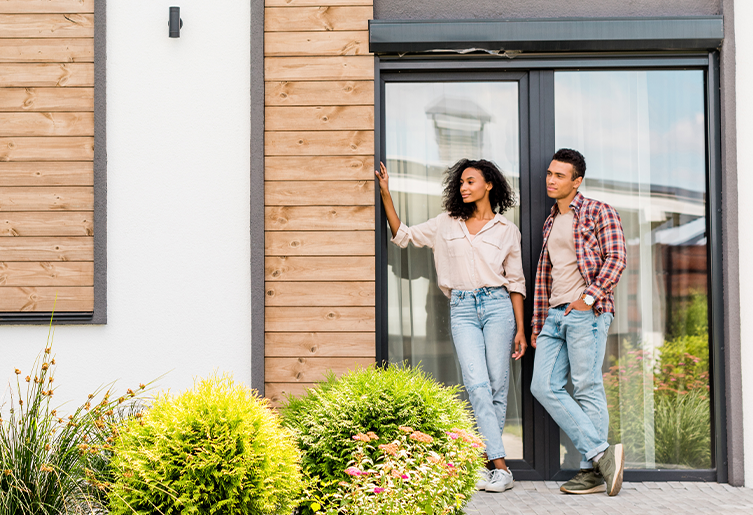 Man and woman leaning against door outside of a house