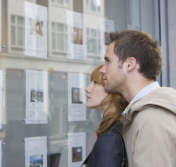 Couple looks at real estate listings in a window