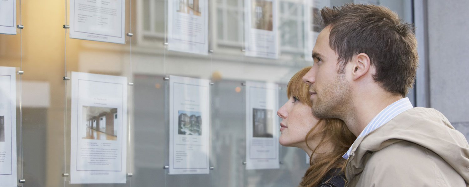 Couple looks at real estate listings in a window